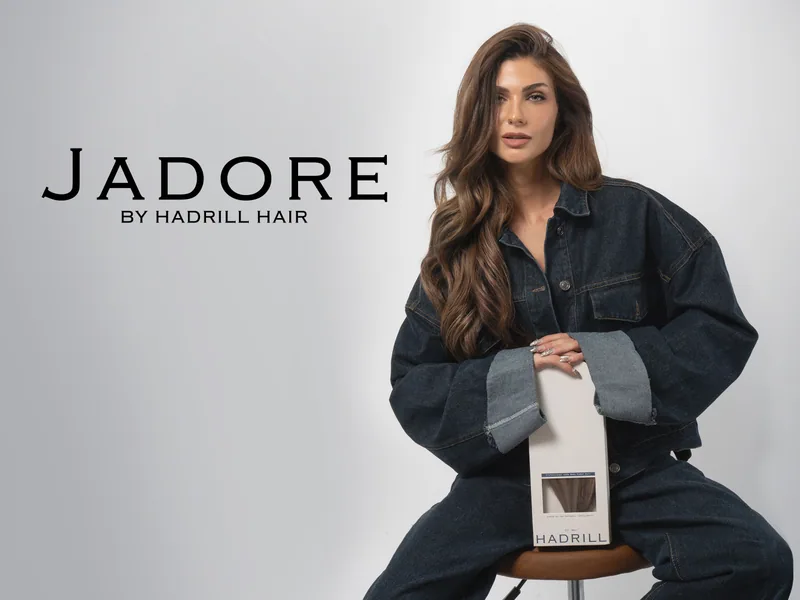 J'Adore by Hadrill Hair campaign image: a model with long brunette waves holding a box of J'Adore hair extensions